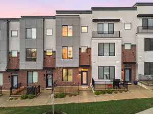 View of front of home with stucco siding, brick siding, and a balcony