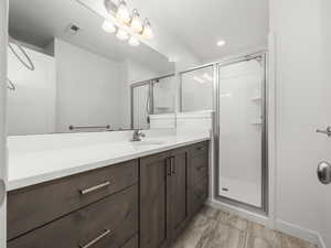 Bathroom with a stall shower, vanity, and recessed lighting
