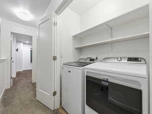 Laundry area with light carpet and washing machine and dryer