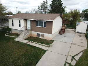 Single story home with brick siding, roof with shingles, concrete driveway, and a front yard