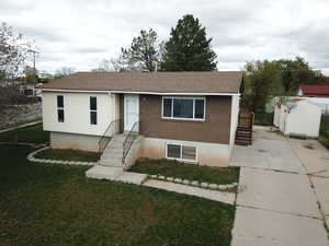 View of front facade with brick siding, a shed, roof with shingles, and concrete driveway