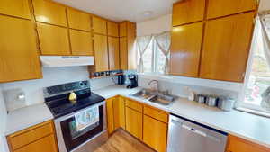 Kitchen with stainless steel appliances, light countertops, wood finish cabinetry, and light wood-type flooring