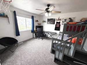 Bedroom with light carpet, a ceiling fan, and a desk