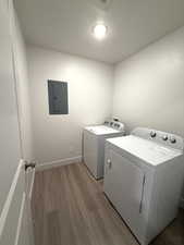 Laundry room featuring light wood finished floors, electric panel, and separate washer and dryer