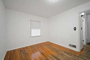 Empty room featuring dark wood-type flooring and baseboards