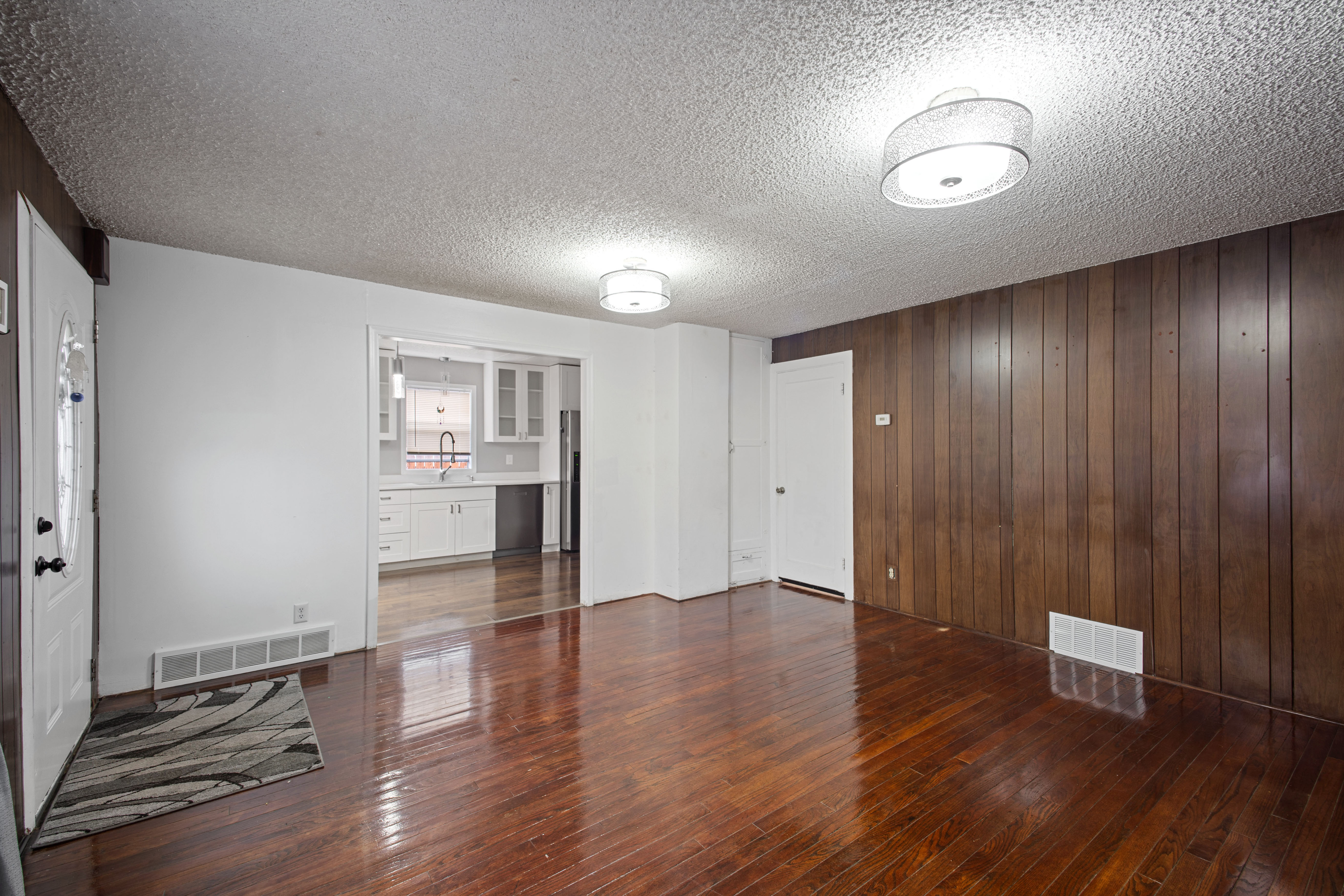 Unfurnished living room with wood walls, dark wood finished floors, and a textured ceiling