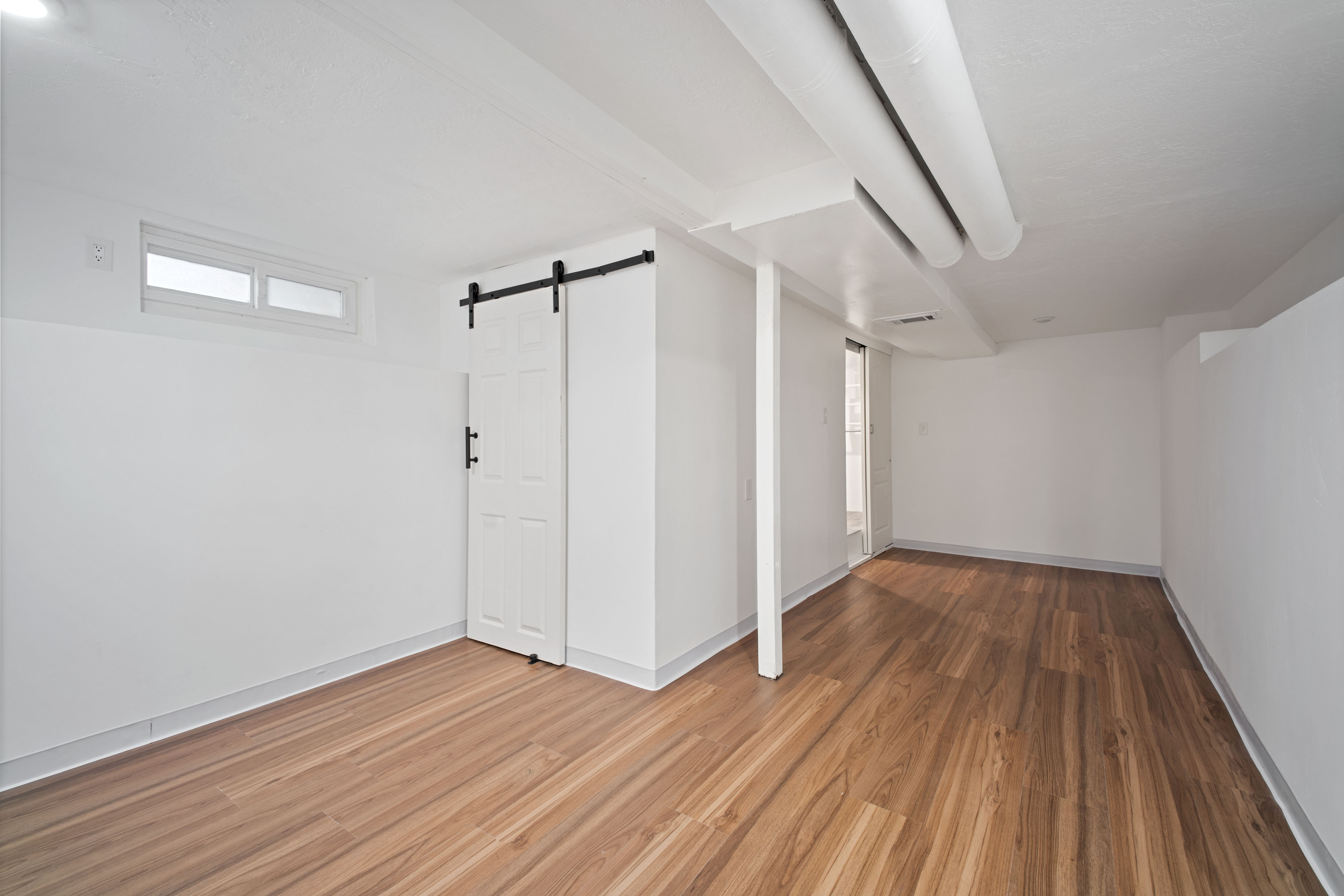 Basement with a barn door and wood finished floors