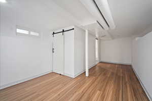 Basement with a barn door and wood finished floors