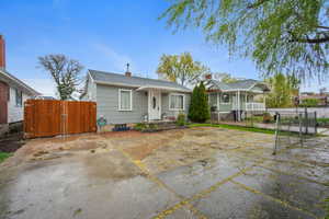 Bungalow-style house featuring a gate, a chimney, roof with shingles, and a patio