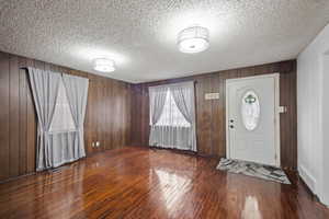 Foyer entrance with dark wood-style floors and a textured ceiling