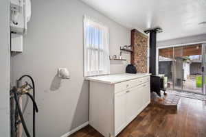 Laundry room featuring white cabinetry, open shelves, and dark wood-style flooring.
