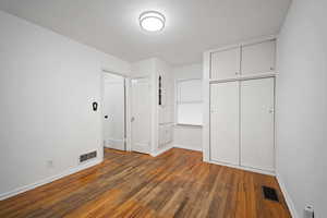 Unfurnished bedroom with dark wood-style floors and a closet