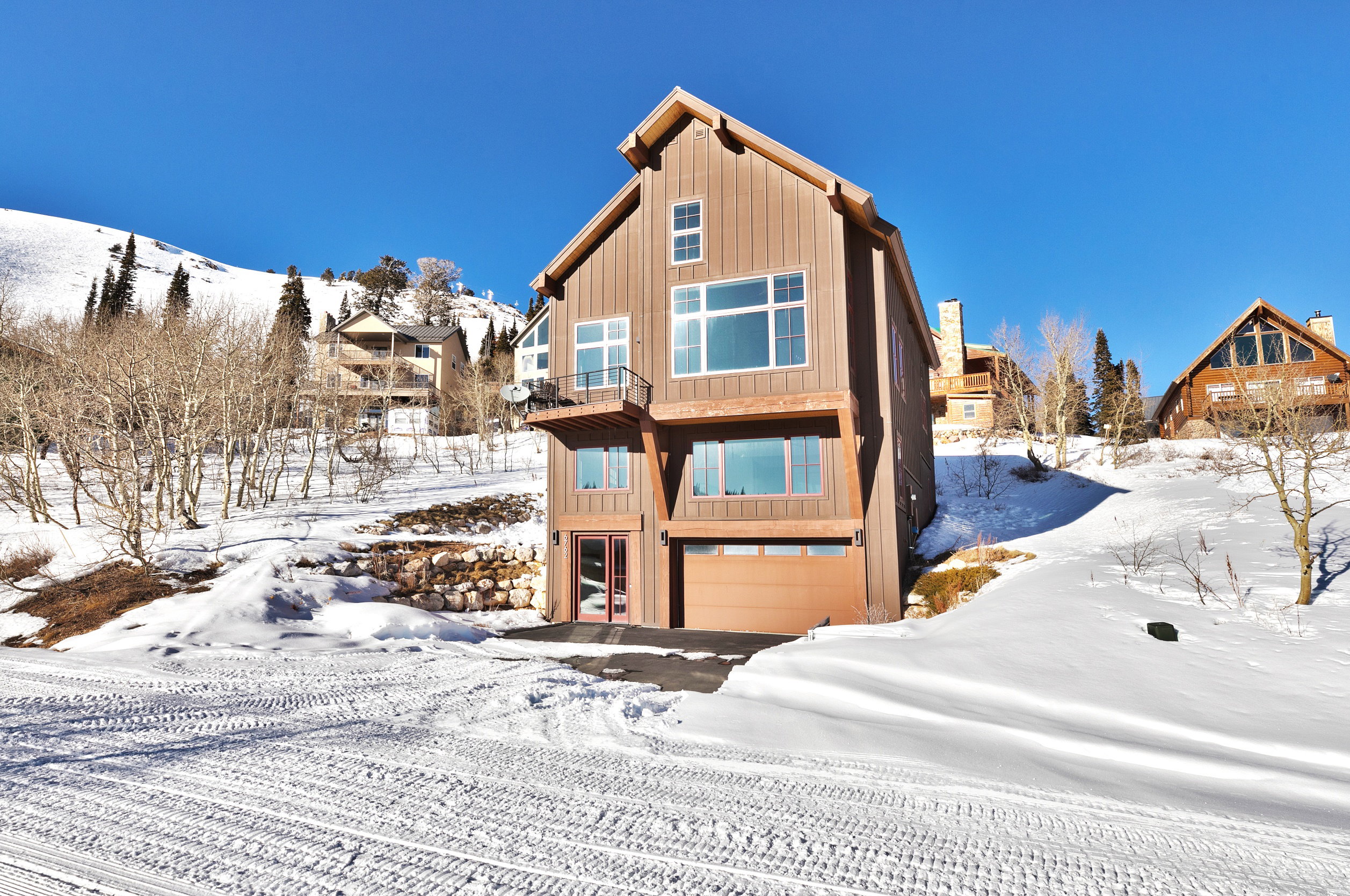 Snow covered rear of property with an attached garage and a balcony