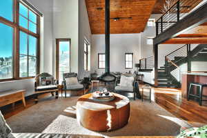 Living room featuring wood-type flooring, a wood stove, a vaulted wood ceiling, and plenty of natural light