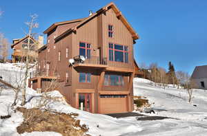 View of front of home with an attached garage, a balcony, and board and batten siding