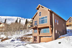 View of front facade featuring an attached garage, board and batten siding, a balcony, and a mountain view