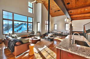 Living room with dark wood finished floors, a high wooden beamed ceiling, and a wood stove
