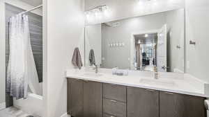 Full bathroom with double vanity and shower / bath combo with shower curtain