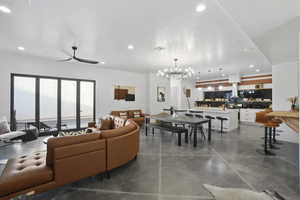 Living room with concrete flooring, hanging lights, and a ceiling fan