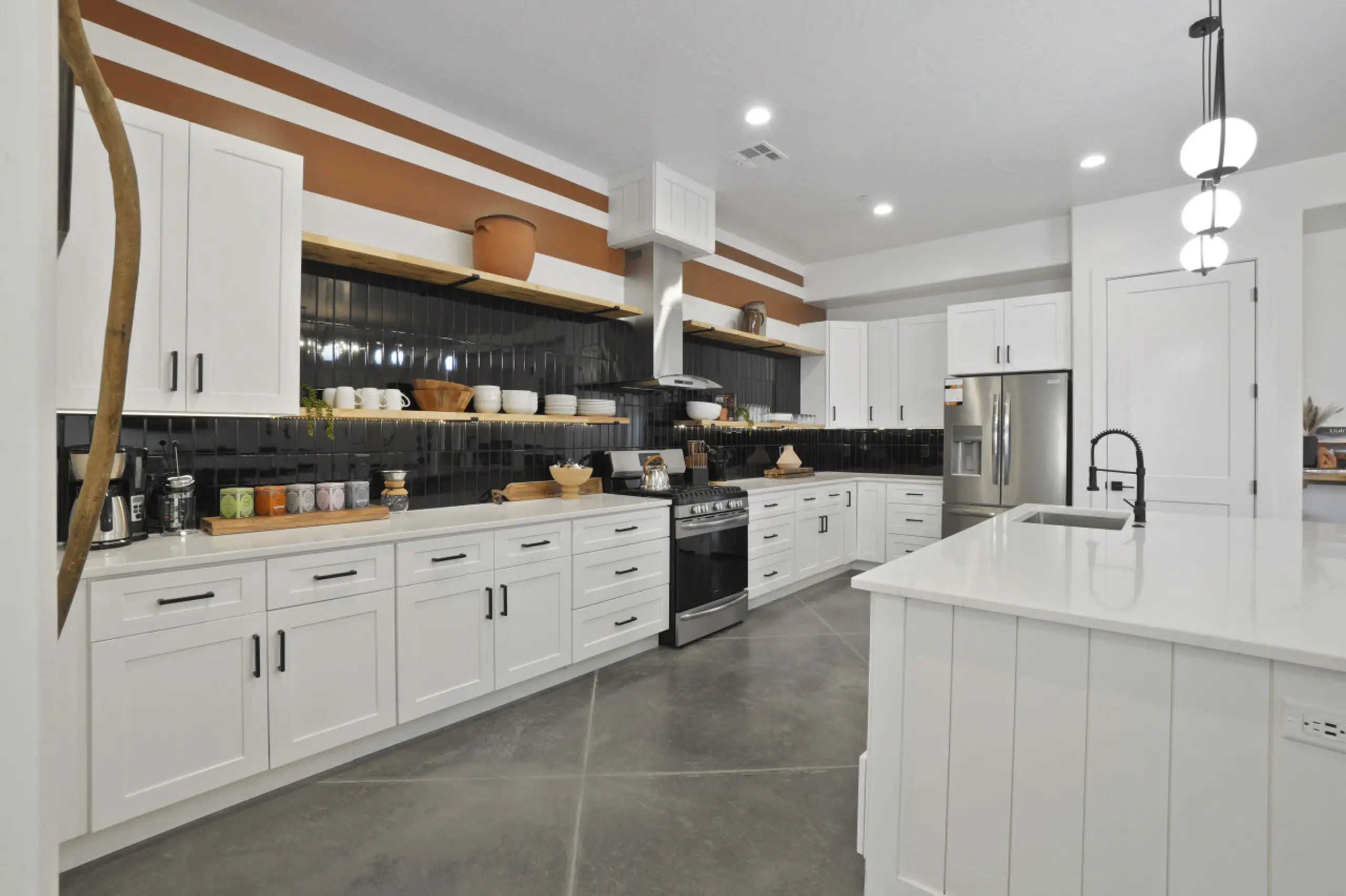 Kitchen featuring decorative backsplash, open shelves, finished concrete flooring, stainless steel appliances, and white cabinets