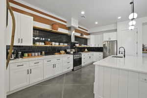 Kitchen featuring decorative backsplash, open shelves, finished concrete flooring, stainless steel appliances, and white cabinets
