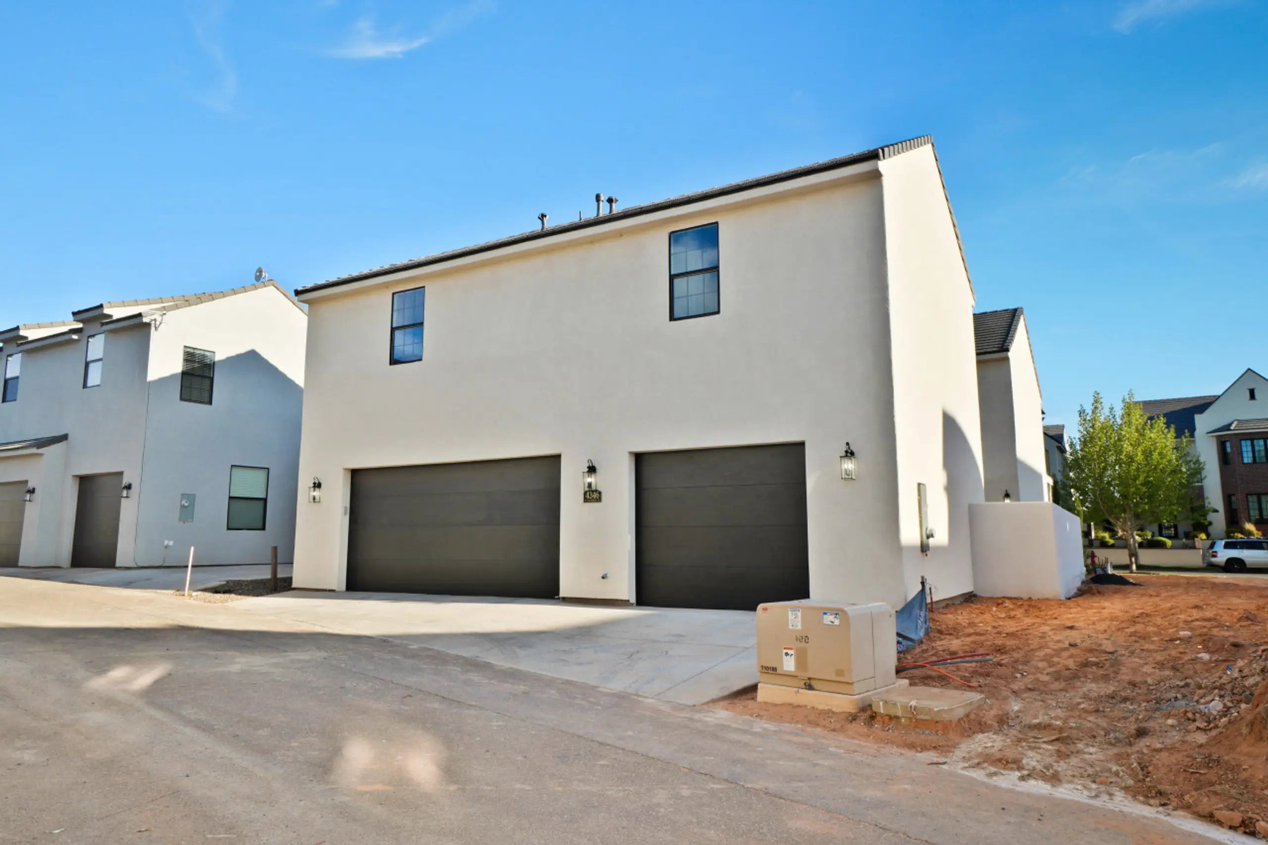 Back of house with an attached garage, concrete driveway, and stucco siding