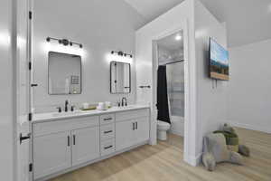 Bathroom featuring double vanity, light wood-style floors, and shower / bath combination with curtain