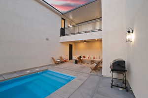 View of swimming pool with an outdoor living space, patio surround, a balcony, a swimming pool, and a grill