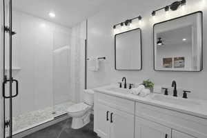 Full bathroom with a shower stall, double vanity, and recessed lighting