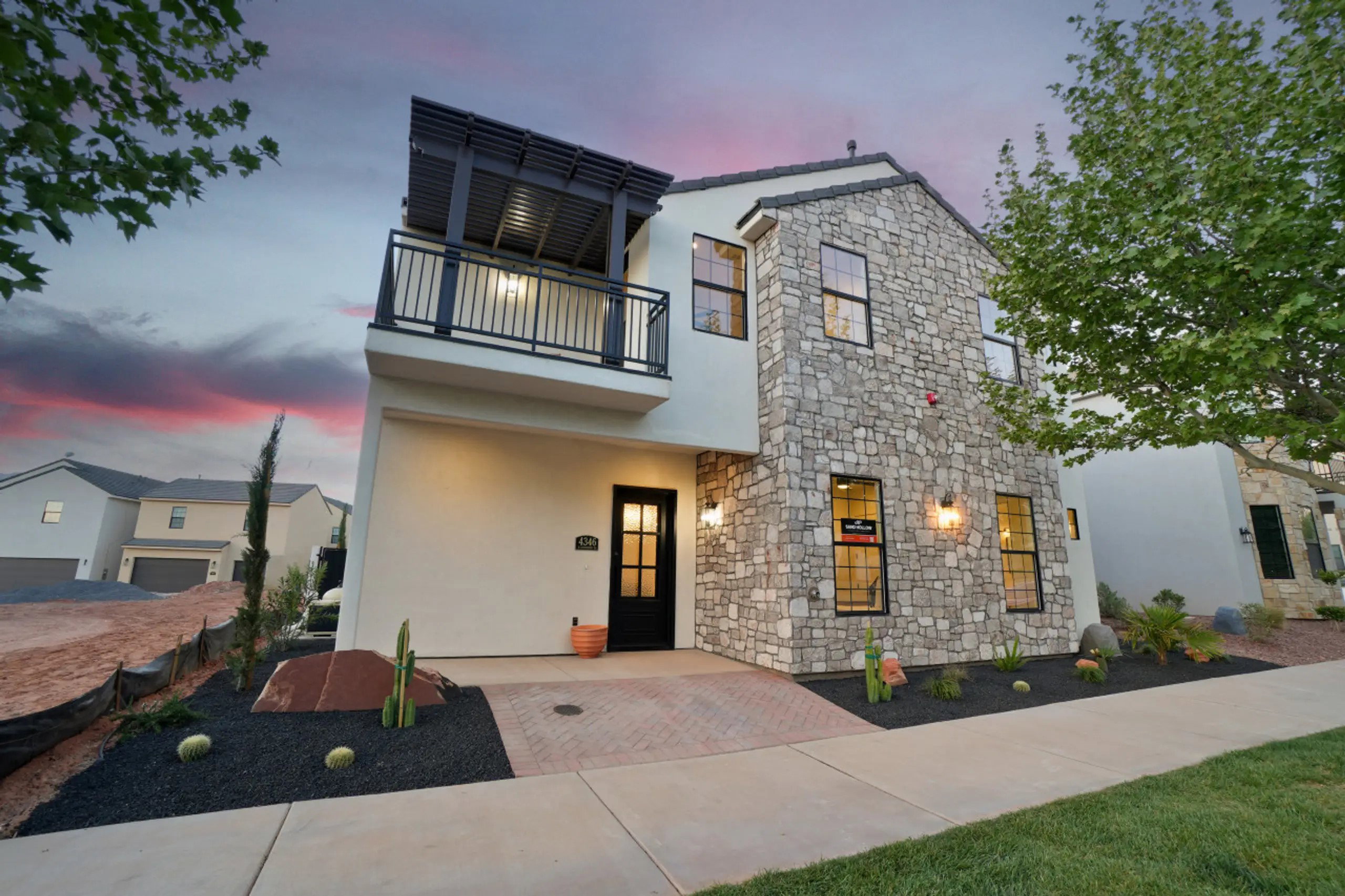 View of front facade featuring stone siding, stucco siding, and a balcony