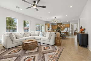 Living room with hanging lights, parquet flooring, and ceiling fan