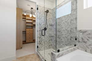 Full bathroom with a stall shower, a garden tub, a spacious closet, and light carpet