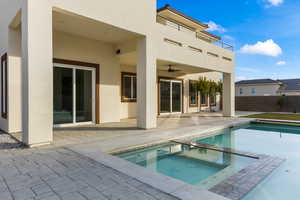 Back of property with a patio area, a pool with connected hot tub, stucco siding, and ceiling fan