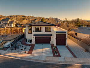 View of front of house featuring stucco siding, concrete driveway, a tiled roof, an attached garage, and stone siding