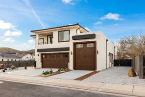 Contemporary home with stucco siding, concrete driveway, a balcony, and a mountain view
