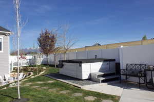 Fenced backyard featuring a patio area and hot tub