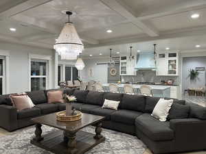 Living area featuring coffered ceiling, suspended lighting, and ornamental molding