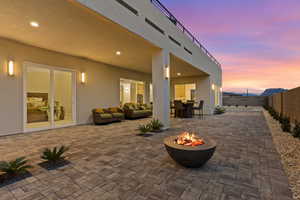 Patio terrace at dusk featuring a patio area, an outdoor living space with a fire pit, and a fenced backyard