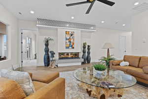Living room featuring a ceiling fan, wood finished floors, a glass covered fireplace, and recessed lighting