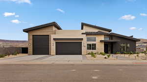 Contemporary house featuring a garage, stone siding, stucco siding, and concrete driveway