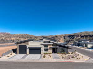 View of front of house with an attached garage, a mountain view, driveway, stucco siding, and stone siding