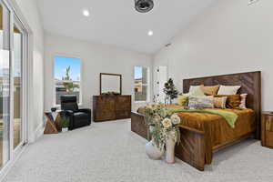 Bedroom with light colored carpet, multiple windows, vaulted ceiling, recessed lighting, and access to outside