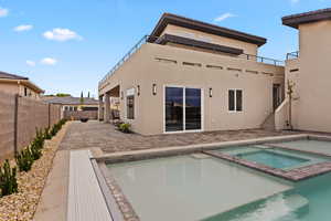 Rear view of house with a patio, stucco siding, a pool with connected hot tub, and a fenced backyard