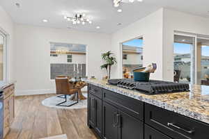 Kitchen featuring light stone countertops, light wood-style floors, black gas cooktop, recessed lighting, and dark cabinets