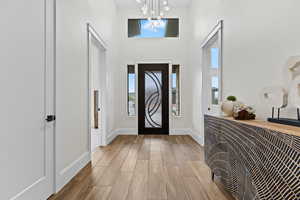 Entryway with light wood-type flooring, a high ceiling, and hanging lights