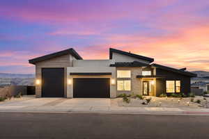 Modern home with stone siding, an attached garage, driveway, stucco siding, and a mountain view