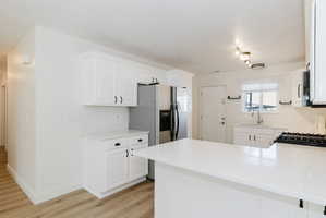 Kitchen with a peninsula, white cabinetry, and light wood-type flooring