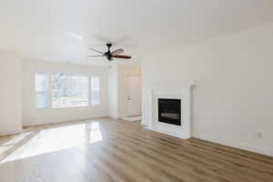 Unfurnished living room featuring light wood-style floors, ceiling fan, and a fireplace