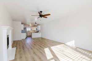 Unfurnished living room featuring ceiling fan, light wood-style flooring, and a fireplace