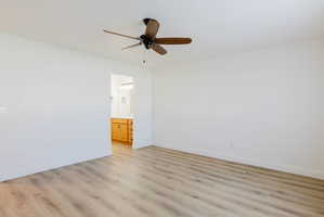 Unfurnished bedroom with light wood-style floors, a ceiling fan, and ensuite bath